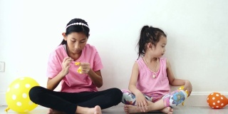 亚洲女孩一起在家里的地板上抽气球，为家庭装饰概念做准备。