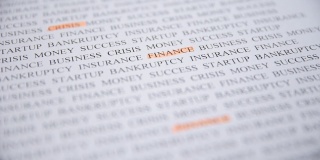 手高亮字金融与橙色标记打印文本，微距拍摄。金融危机的概念