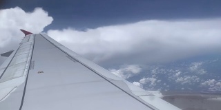 飞机在蓝天白云之上飞行。飞机窗外的美景;小翼在Cloudscape背景上。