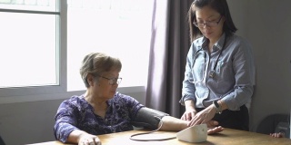 亚洲医疗保健工作者在家中测量一位老年妇女的血压