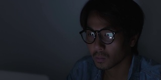 亚洲休闲商人戴眼镜打字笔记本电脑和触摸下巴在办公室工作
