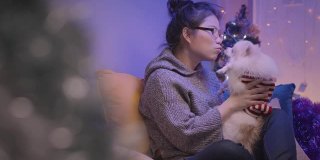 年轻的亚洲迷人的女性女人玩他的大腿狗在客厅的沙发周末假日活动圣诞节日概念