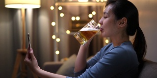 亚洲女人在视频电话会议与朋友做快乐的时间，在她的手啤酒