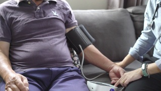 女医生检查一个资深亚洲男性病人的血压在家视频素材模板下载