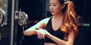 年轻的亚洲女人在锻炼手臂机器