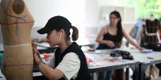 亚洲华人大学时装学生在课堂上研究他们的时装设计