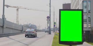 位于ul的绿色屏幕广告牌。附近有一座公路桥，汽车可以在上面行驶
