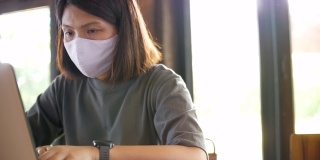 在新冠病毒传播期间戴口罩在家工作的年轻女性