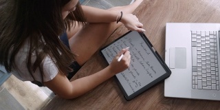 COVID-19大流行期间的在家教育。专注于用笔记本电脑上在线课程的学生。青少年在线学习和在她的数字平板电脑上做笔记。社会距离。