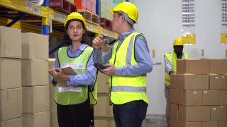 亚洲仓库经理持有条码扫描仪培训实习生女工在仓库工厂控制库存和检查清单库存。新员工向主管学习工作视频素材模板下载