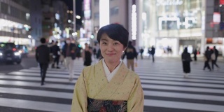 身着和服的日本妇女站在夜间城市的斑马线上