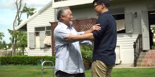 亚洲老人带着沃克和成年的儿子一起走在加登的家里。老人残疾行走和照顾年轻人帮助在后院。保健家庭生活方式