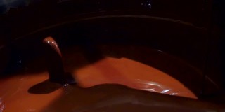 熔化的巧克力在特殊的搅拌机中与浆棒混合。特写镜头