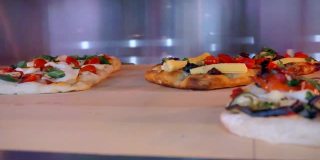 几种不同馅料的披萨在烤箱里烤熟。特写镜头