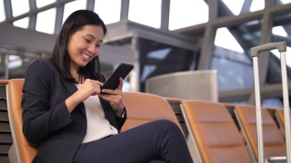 亚洲女商人在机场使用智能手机视频素材模板下载