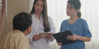 亚洲女医生和护士来到检查室，向坐在康复室床上的男病人询问健康问题。女医生讨论并给男人保健建议。