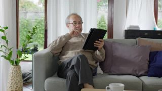 亚洲退休老人用平板电脑在线转账或金融支付，阅读文字，微笑或大笑，快乐和积极。资深亚洲人，具有数字技术理念视频素材模板下载