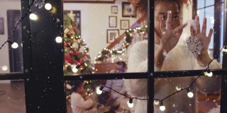 快乐的女孩一边在窗前装饰雪花，一边先下大雪，构思冬天和圣诞节的场景
