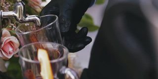 戴手套的酒保在玻璃杯里盛满美味的热葡萄酒