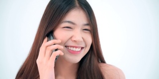 迷人的亚洲女孩与智能手机聊天在工作室拍摄，孤立在一个白色的背景。