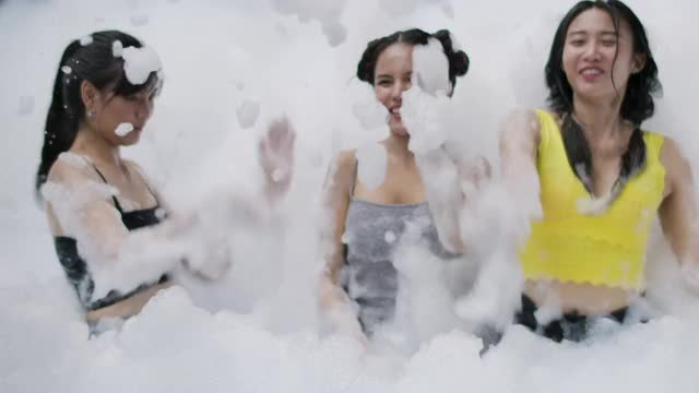 年轻女子在泳池里玩泡沫和泡泡的肖像。