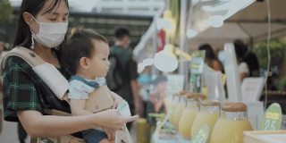 年轻的妈妈和她的儿子在泰国的街头小吃市场买甘蔗汁