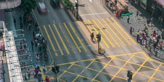 在中国香港尖沙咀区，人们和出租车穿过一个非常繁忙的十字路口