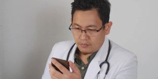 亚洲男医生在网上做研究，浏览上网他的手机