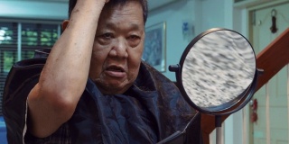2019冠状病毒病大流行:在家里剪祖母头发的妇女