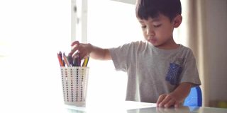 亚洲男婴在家学习在纸上画画