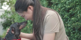 一个东南亚妇女在后院和她的狗玩