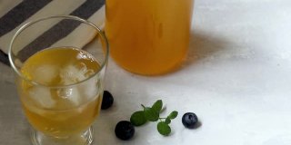 喝冷的，健康的，自制的发酵康普茶与天然益生菌的特性。在明亮的背景下，在玻璃碗中加冰饮用。