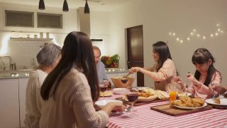 幸福的家庭时间和关系，亚洲大家庭有一个小聚会，一起在家里吃东西。爷爷很高兴看到他的孩子和侄子在家里的餐桌上吃饭，分享食物。视频素材模板下载