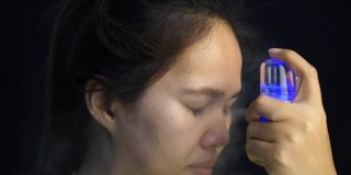 亚洲妇女使用喷雾机进行面部护理。