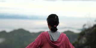 年轻的亚洲女性在山顶愉快地呼吸着新鲜空气