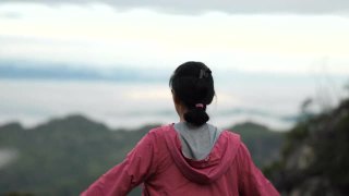 年轻的亚洲女性在山顶愉快地呼吸着新鲜空气视频素材模板下载