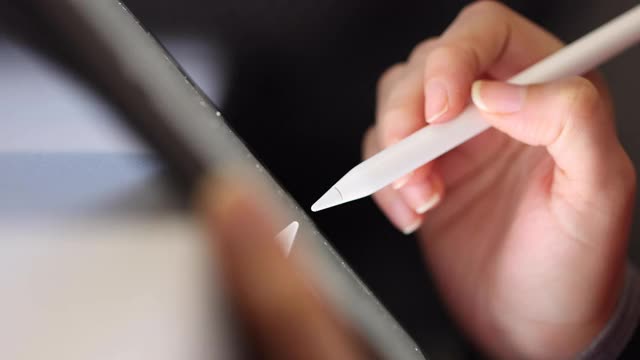近距离的女性手使用数字笔书写在数字平板屏幕上