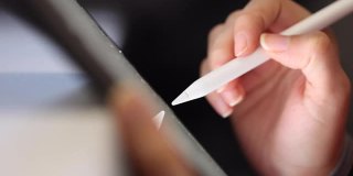 近距离的女性手使用数字笔书写在数字平板屏幕上