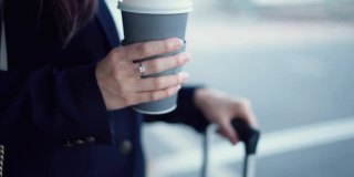 投资者女士拿着咖啡杯在机场出发区等待机场班车