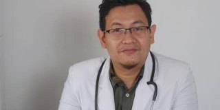 亚洲男医生对着摄像机说话，在视频通话中给出建议。在线医生远程医疗远程保健概念