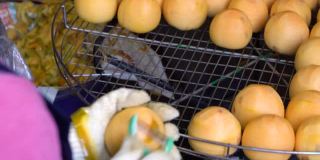 一名女工用削皮器削柿子，并把它们放在筛子里。