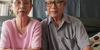 亚洲老夫妇和他们的孩子微笑着对着镜头说话。老年人学习使用智能手机app和互联网在线技术进行远程会议。