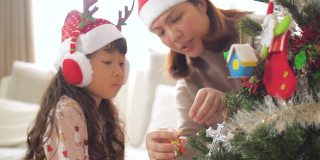 小女孩和妈妈在圣诞节用装饰品装饰圣诞树
