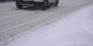 汽车在城市积雪的道路上行驶，慢镜头。运输，冬季轮胎，慢动作