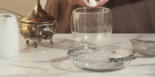 玻璃盘子上的棉花糖靠近大理石背景。女人准备热巧克力和棉花糖