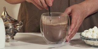 在玻璃杯中混合热巧克力饮料，近距离视频，大理石背景