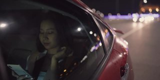 女人用电话在汽车里通过城市晚上回家