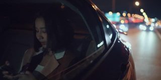 女人用电话在汽车里通过城市晚上回家