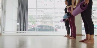 一群年轻的亚洲妇女在房间里滚动练习垫作为早上的背景。运动的概念。