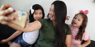 家人用手机视频通话。亚洲母亲与小女儿进行远距离交流